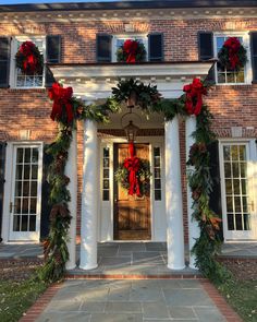 the front entrance to a brick house decorated for christmas with wreaths and poinsettia