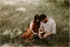 a man and woman sitting in the grass with a baby