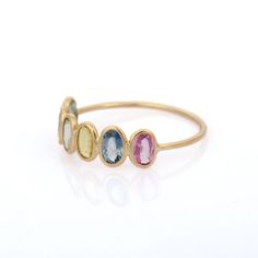 three stone ring in yellow gold, pink and blue sapphires on a white background