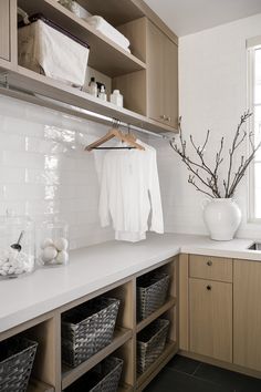 a white kitchen with wooden cabinets and shelves filled with dishes, towels and other items