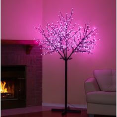 a living room with a white couch and a pink lit tree in front of a fireplace