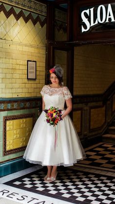 a woman standing in front of a store with a bouquet on her head and wearing a white dress