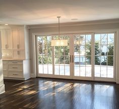 an empty living room with wood floors and sliding glass doors that lead out to the backyard