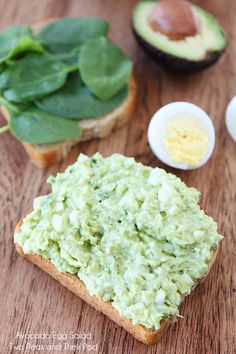 avocado spread on bread with spinach leaves and an egg in the background