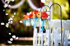 rows of white chairs with flower arrangements on them