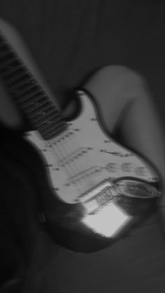 a person's hand holding an electric guitar in black and white with music notes on it