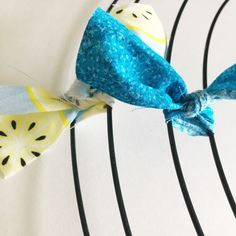 a blue and yellow bow tie sitting on top of a piece of fabric next to a white wall