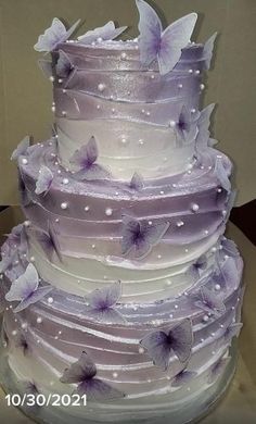 a three tiered cake with purple butterflies on it