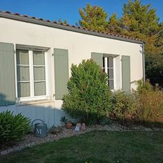 a white house with green shutters and plants