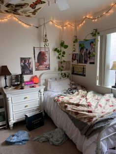 a bedroom with lights strung from the ceiling and pictures on the wall above the bed