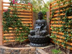 a buddha statue sitting on top of a potted planter next to a wooden fence