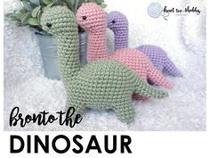 three crocheted dinosaurs sitting next to each other in front of a potted plant