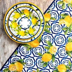 two plates with lemons and leaves on them next to a blue and white plate