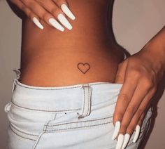 a woman with white nails and a heart tattoo on her stomach