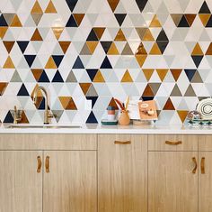 a kitchen with wooden cabinets and tiled backsplash, white counter tops and gold handles