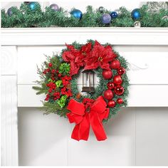 a christmas wreath with red and green ornaments on top of a white fireplace mantel