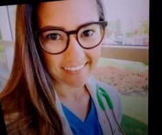 a woman with glasses and a green stethoscope on her left side is smiling at the camera