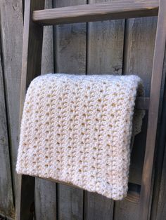 a white crocheted blanket hanging on a wooden chair