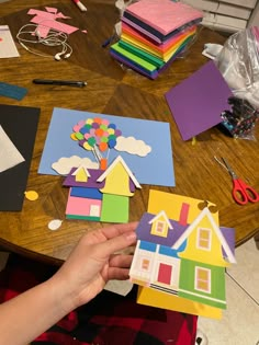 someone is making houses out of construction paper on a table with scissors and other crafting supplies