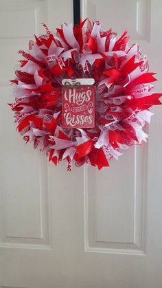 a red and white wreath hanging on a door with the words hugs are kisses written on it