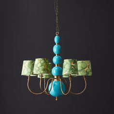 a chandelier with green and blue lamps hanging from it's sides on a black background