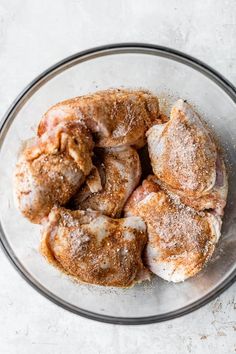 a glass bowl filled with cinnamon rolls covered in powdered sugar on top of a white table