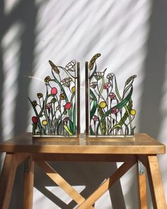 two vases sitting on top of a wooden table next to a shadow cast wall