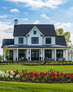 a large white house sitting on top of a lush green field with lots of flowers