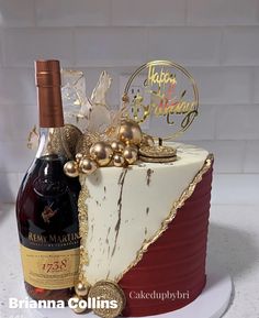 a birthday cake with a bottle of wine and decorations on the top is decorated in gold