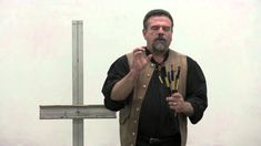 a man standing in front of a cross holding paintbrushes