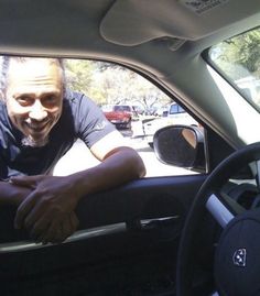 a man sitting in the driver's seat of a car with his hand on the steering wheel