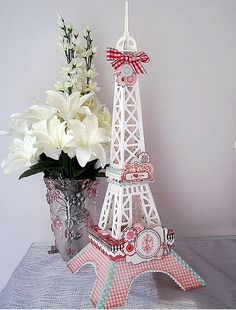 the eiffel tower is made out of paper and has flowers in vases next to it