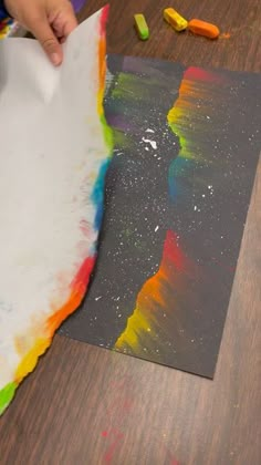 a child is painting with colored crayons on the paper that he has made