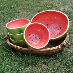 three bowls sitting on top of a basket in the middle of some grass with watermelon bowls serving set