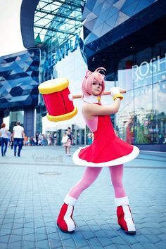 a woman dressed in pink and white holding a red drum