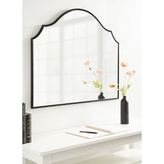 a mirror sitting on top of a table next to a vase with flowers in it