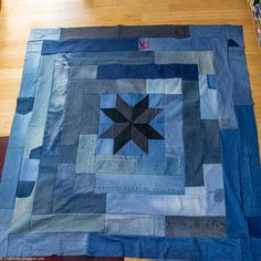 a blue and black patchwork quilt on a wooden floor