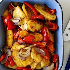 a blue dish filled with potatoes, onions and peppers