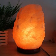 a himalayan rock lamp sitting on top of a wooden table next to a potted plant