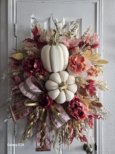 a white pumpkin decorated with flowers and ribbons hangs on a doorknob in front of a doorway