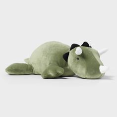 a green stuffed animal with horns laying down