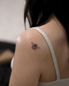 a woman's back shoulder with a small tattoo of a bee on the left arm