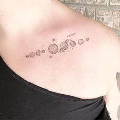 a woman with a tattoo on her shoulder that has the planets and stars in it