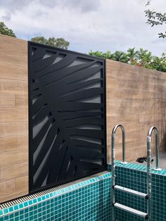 an outdoor swimming pool with tiled walls and blue tiles on the ground, next to a wooden fence