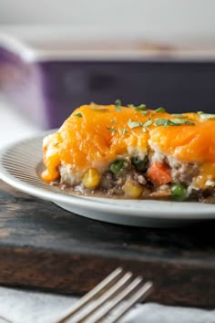 a white plate topped with an enchilada covered in cheese and veggies