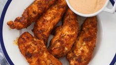 some chicken sticks are on a plate with dipping sauce