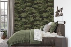 a camo wallpaper in a bedroom next to a bed with pillows on it