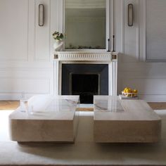 a living room with white walls and a fireplace in the center, surrounded by marble furniture