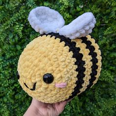 a hand holding a yellow and black stuffed animal