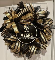 a vegas knights wreath hanging on the front door with black and gold ribbon around it